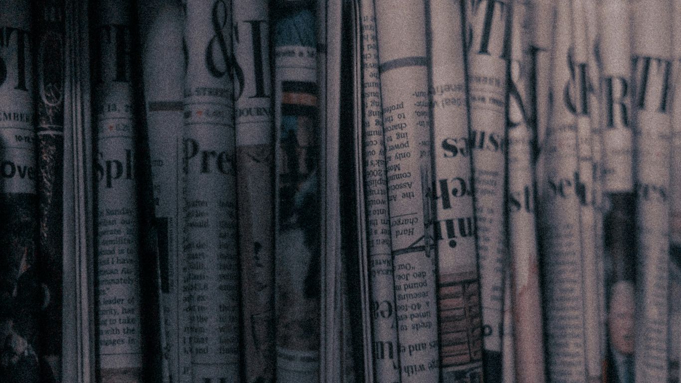 a row of newspapers sitting on top of a shelf