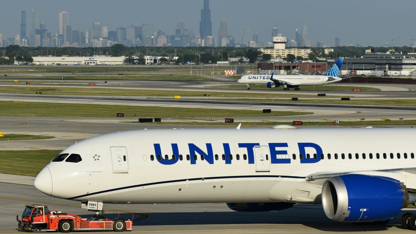 a united airlines plane on a runway with a city in the background