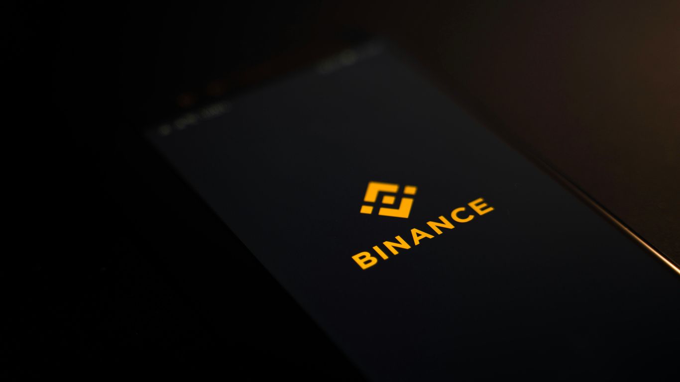 A smartphone displaying the Binance logo against a dark background.