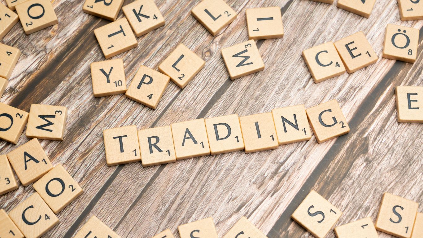 scrabble tiles spelling the word trading on a wooden surface