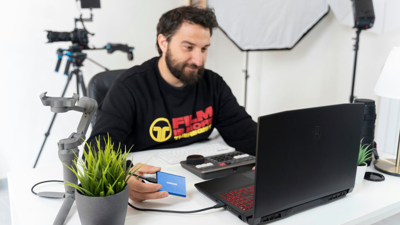 a man sitting at a desk with a laptop and a camera