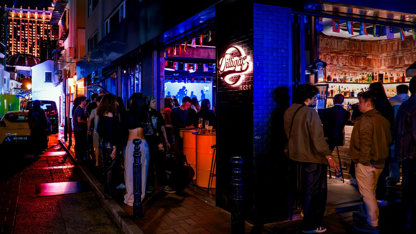 People queue outside a vibrant bar at night.