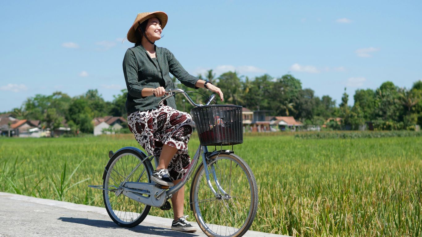 woman in gray long sleeve shirt riding on bicycle on road during daytime