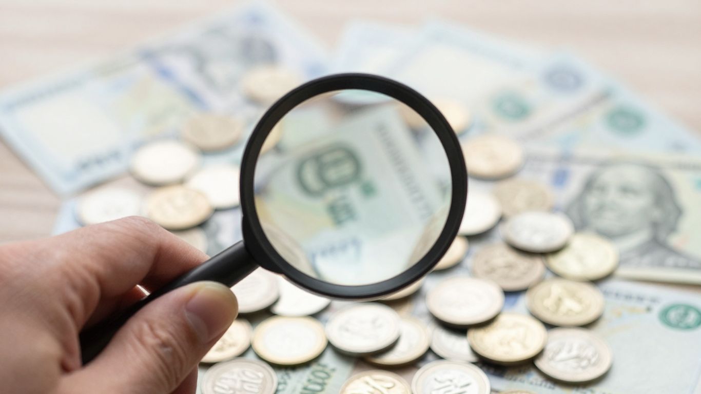 Münzen und Banknoten unter einer Lupe