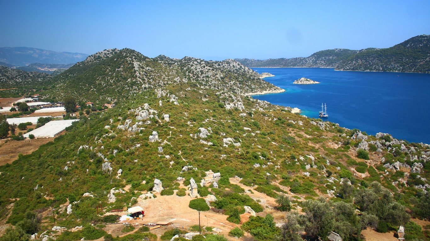 Green hills meet the blue ocean with boats