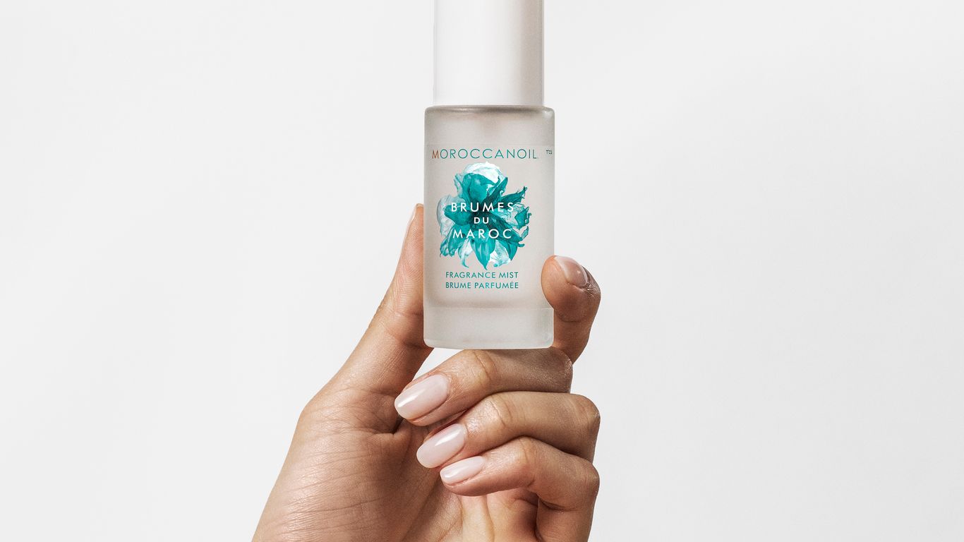 Hand holding a bottle of Moroccanoil hair product.