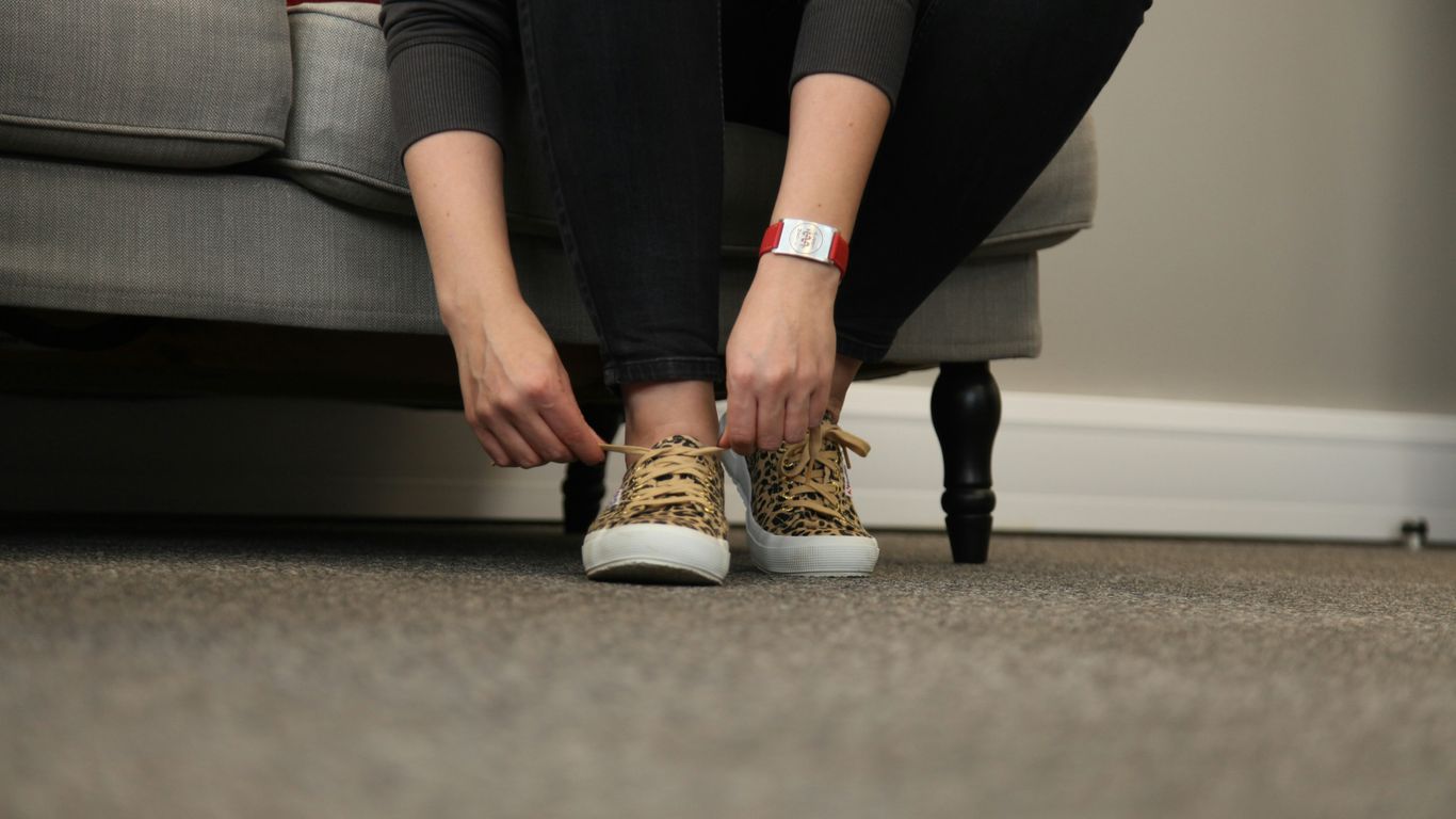woman in black pants and white and brown shoes sitting on black and red couch
