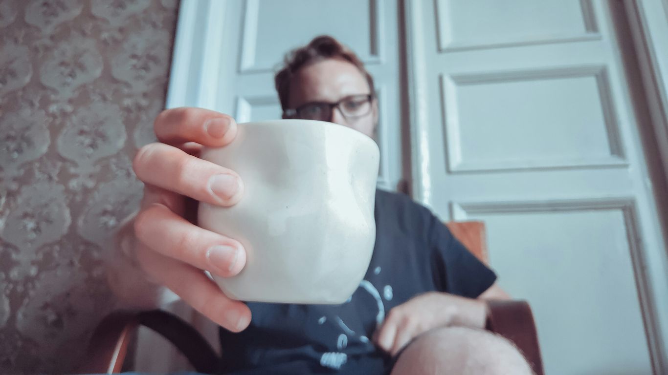 man holding white ceramic cup close-up photography