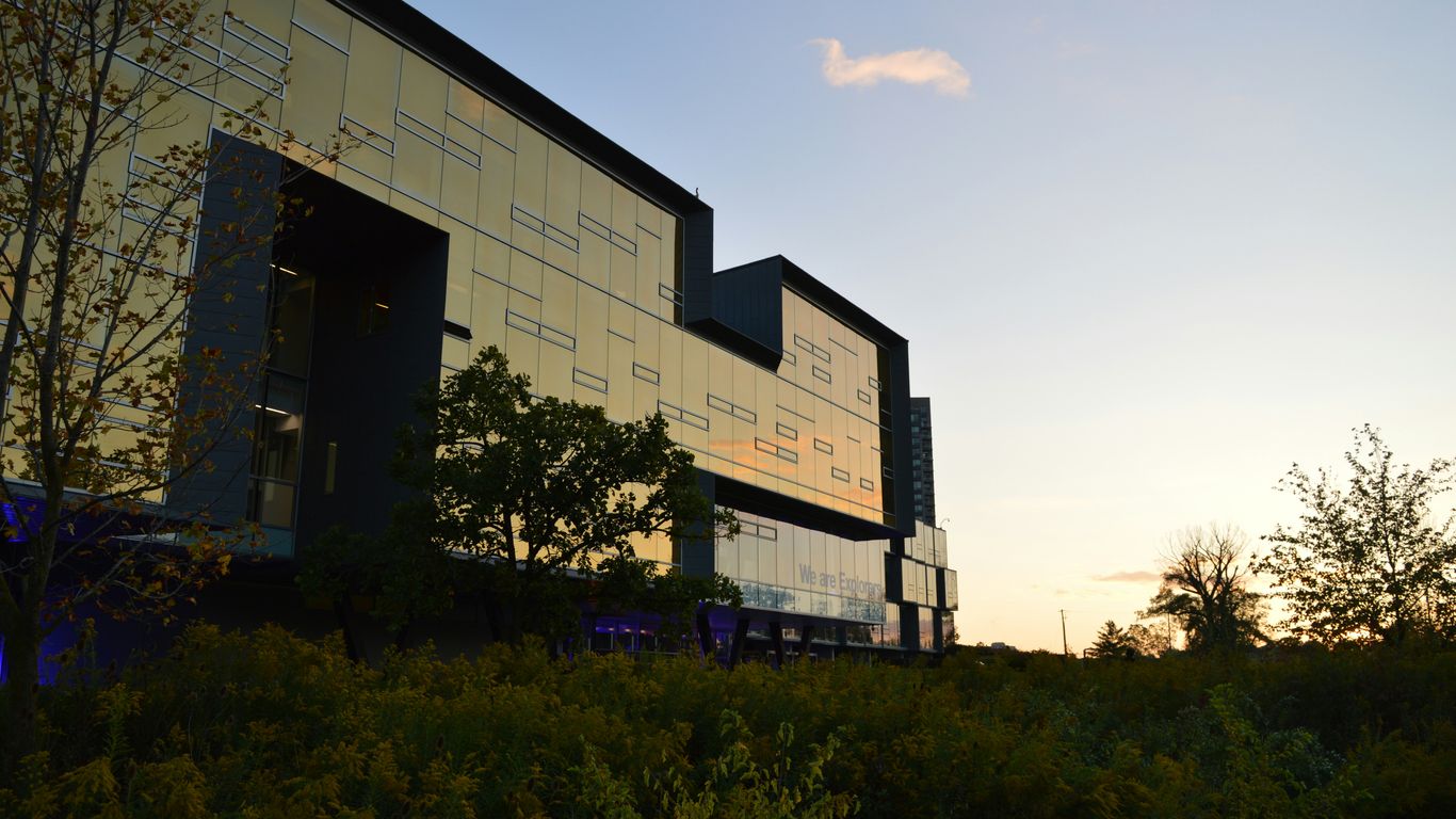 Modern building facade at sunset with trees.