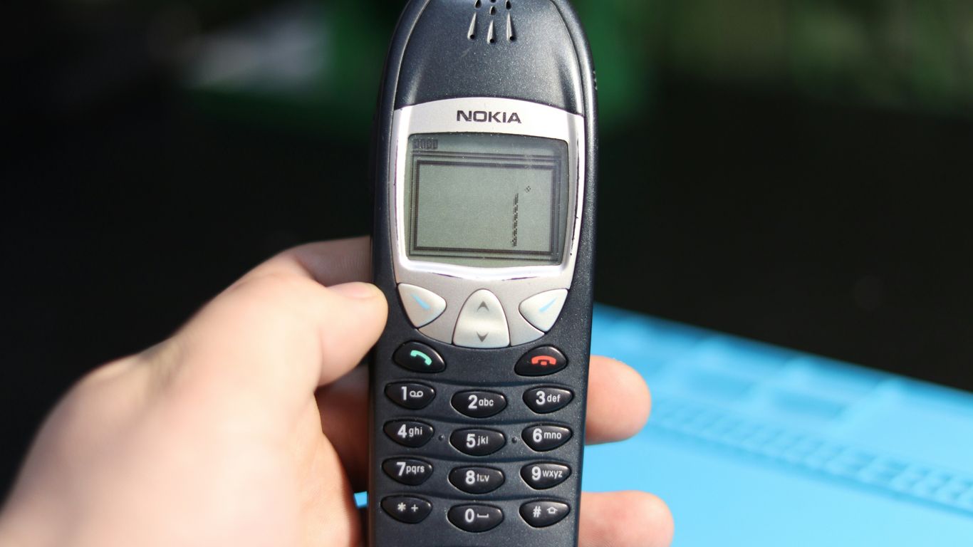 A hand is holding an old nokia cell phone.