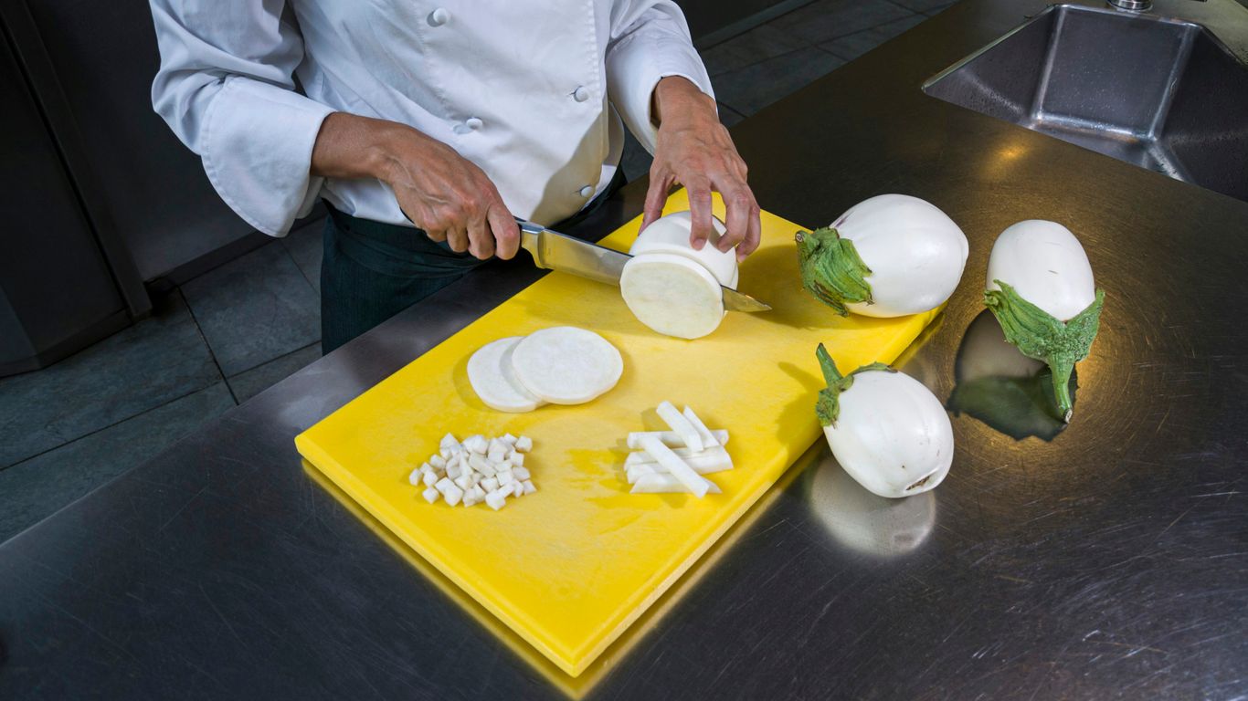 a chef chopping onions on a yellow cutting board