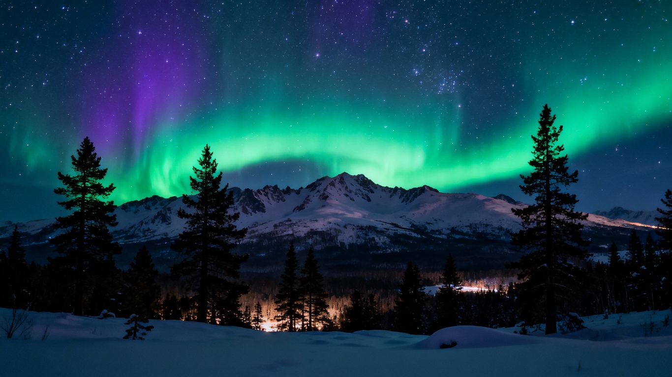 Vibrant aurora borealis over snowy mountains at night.
