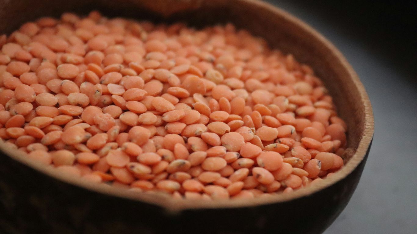 A wooden bowl filled with red beans on top of a table