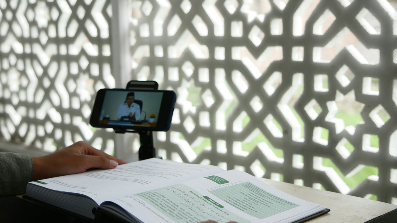 a person sitting at a desk with a book and a cell phone
