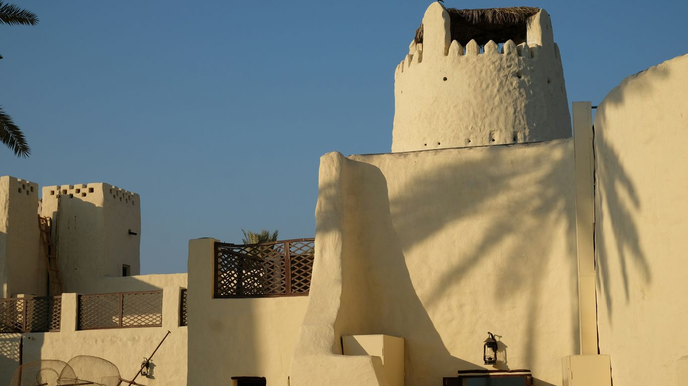 Traditional white buildings with palm tree shadows.