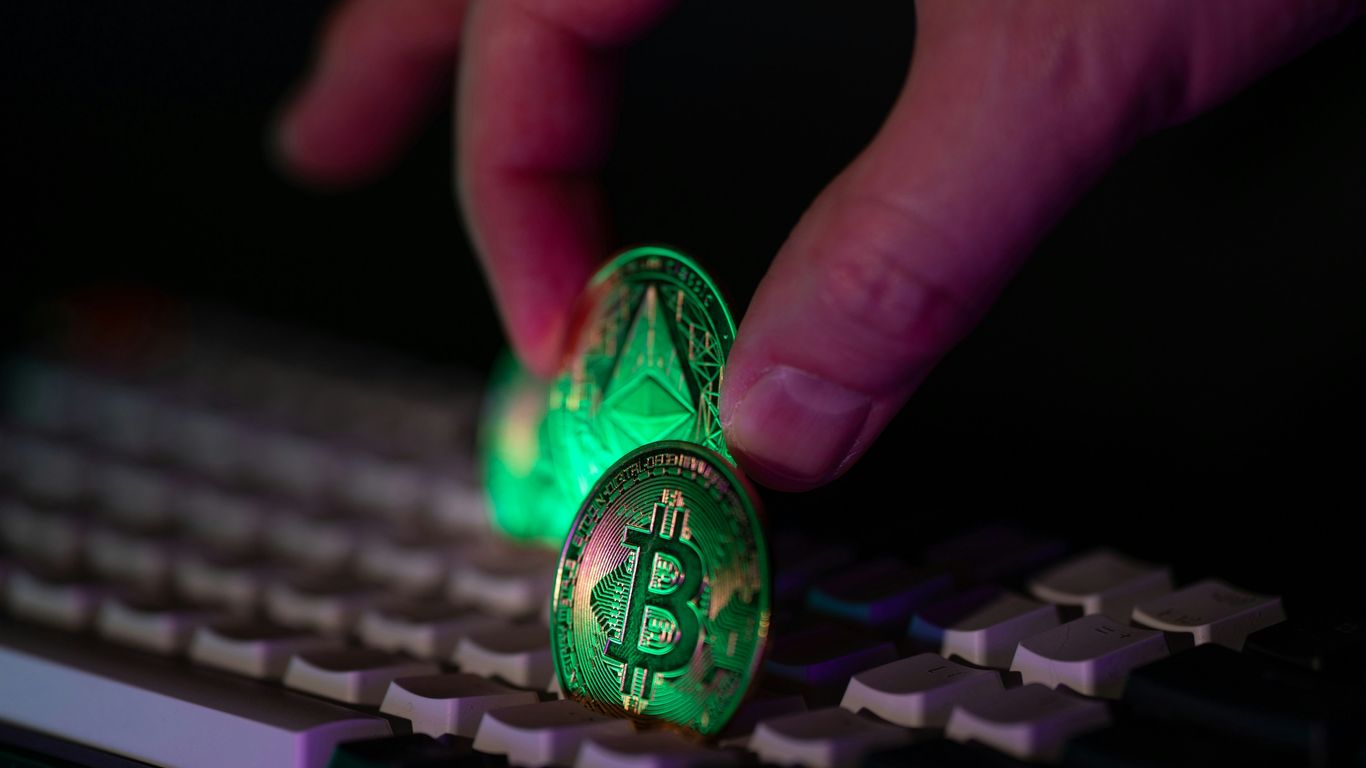 Hand placing glowing crypto coins on a keyboard.