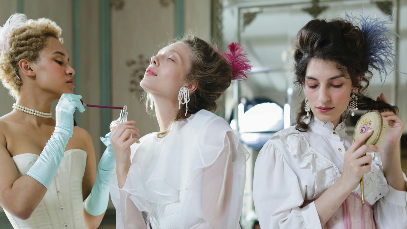 Three women in vintage attire preparing for an event.