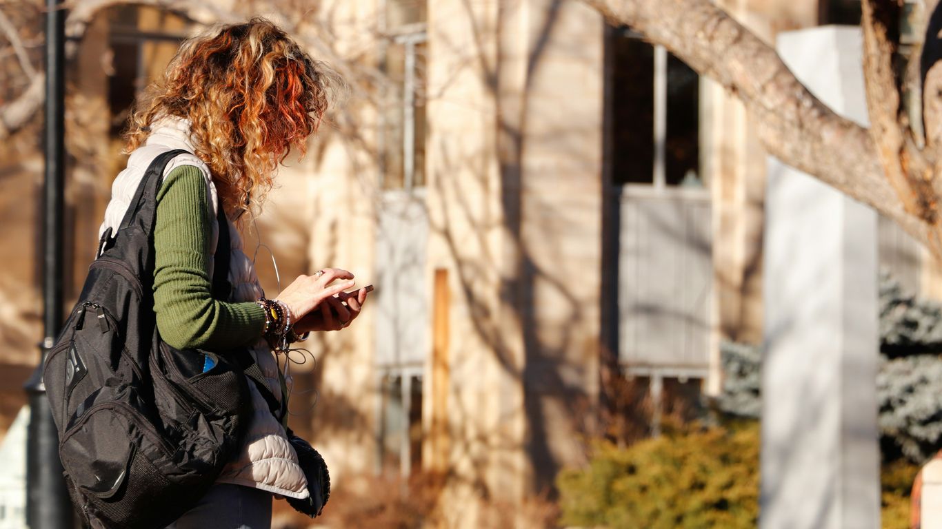 woman in green long sleeve shirt and black pants standing near brown tree during daytime