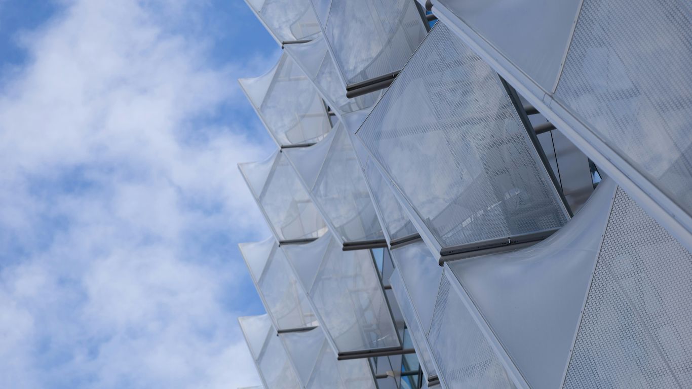 Modern building facade with white geometric panels and sky.