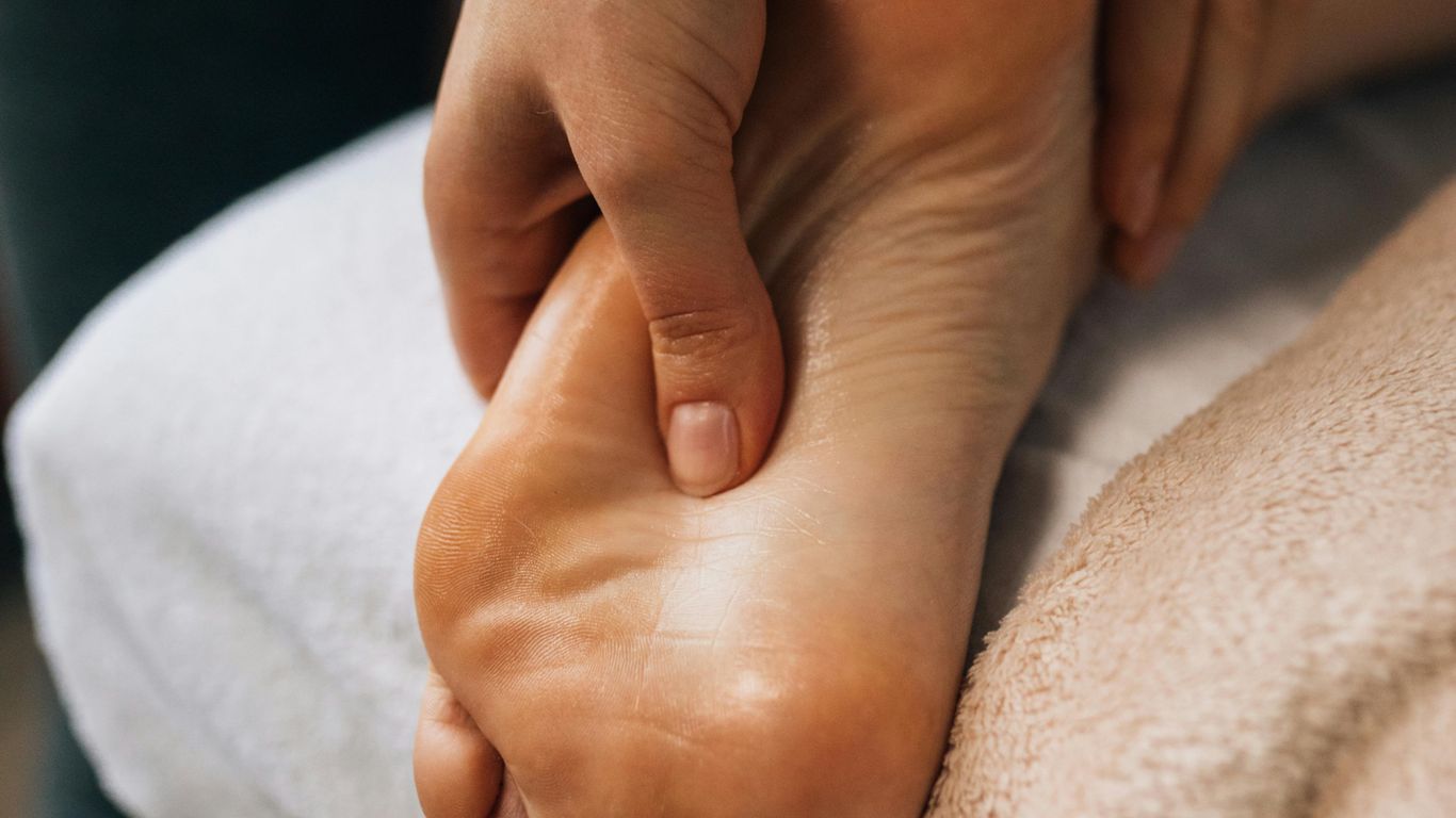 A person is receiving a relaxing foot massage on bed.