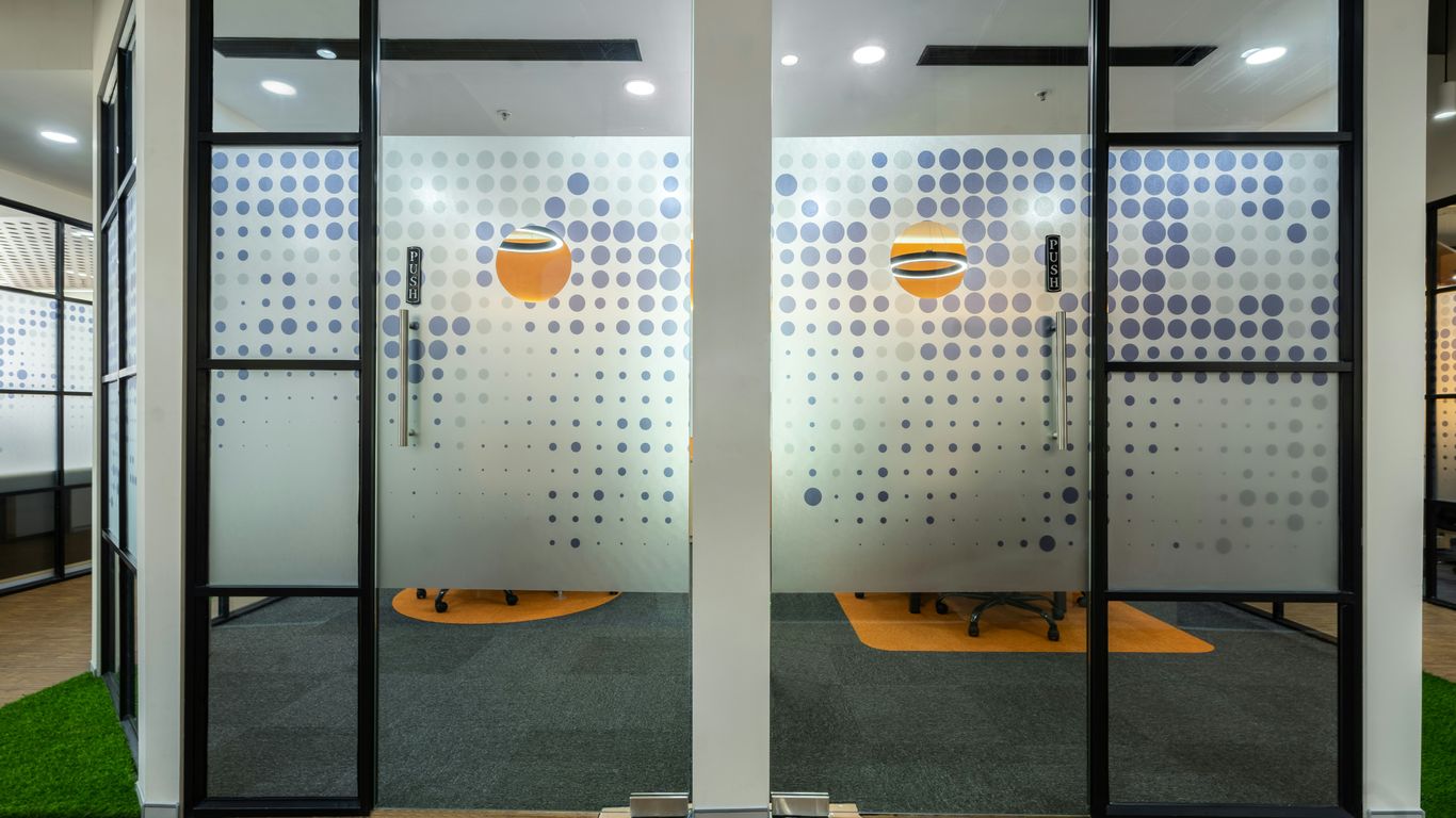 an office cubicle with two glass doors and a grass area