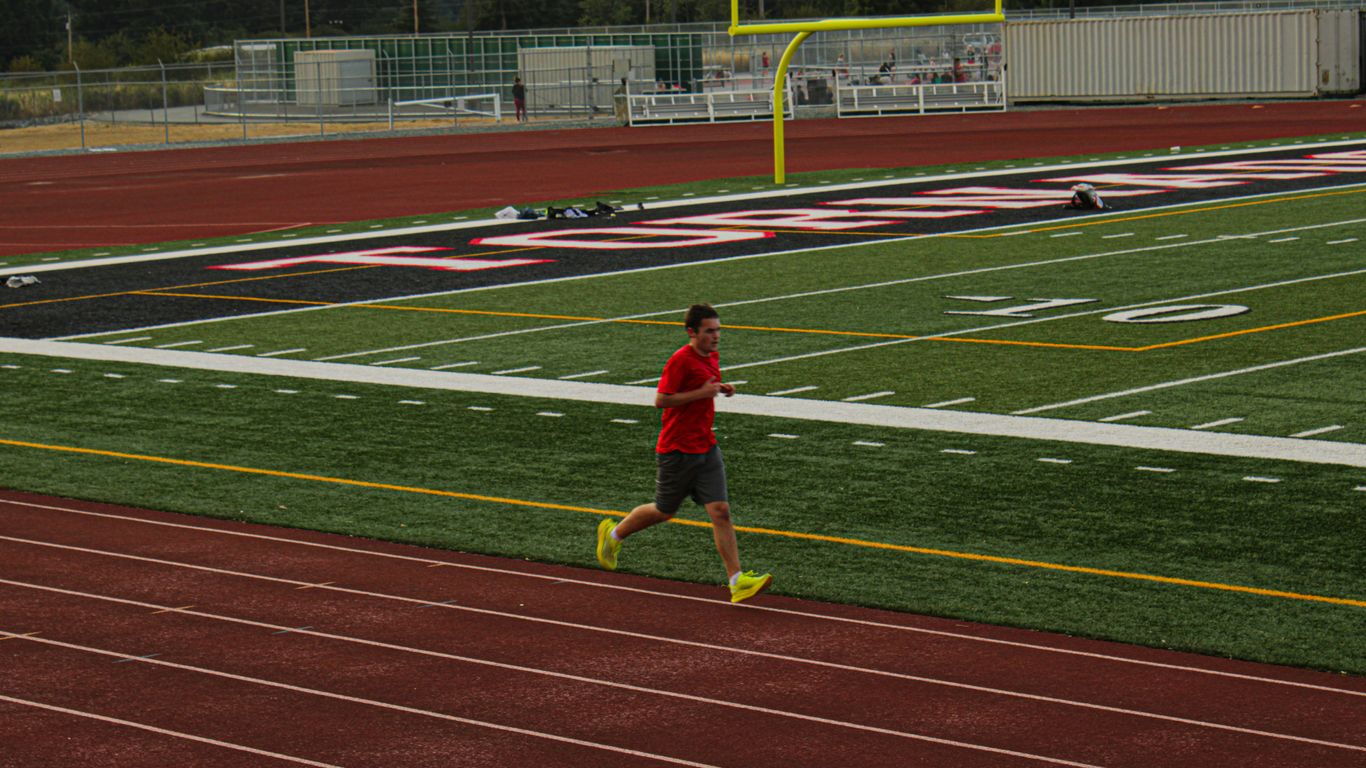 A man in a red shirt is running on a track