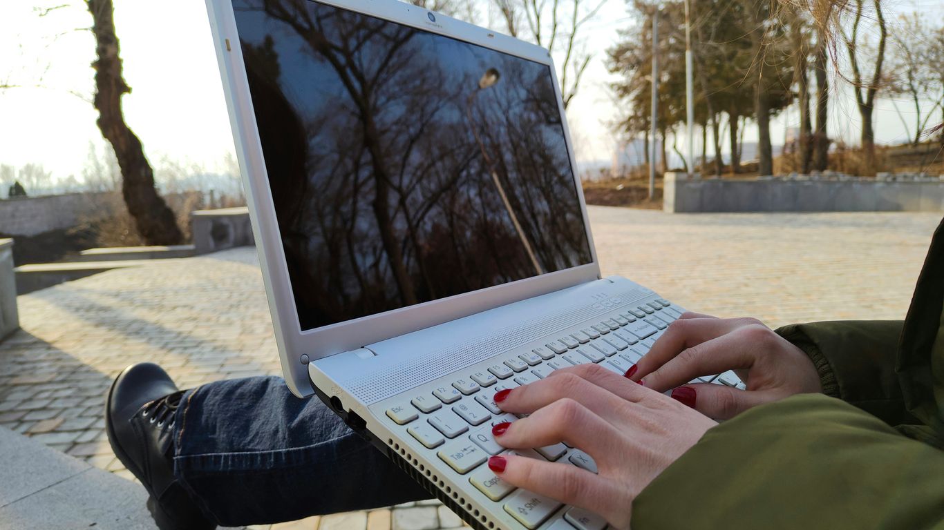 a person typing on a laptop on a bench