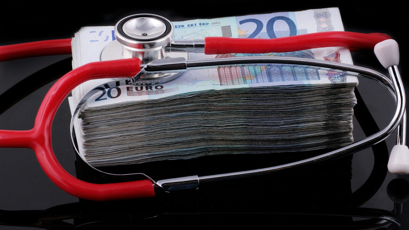 a medical stethoscope resting on a stack of money