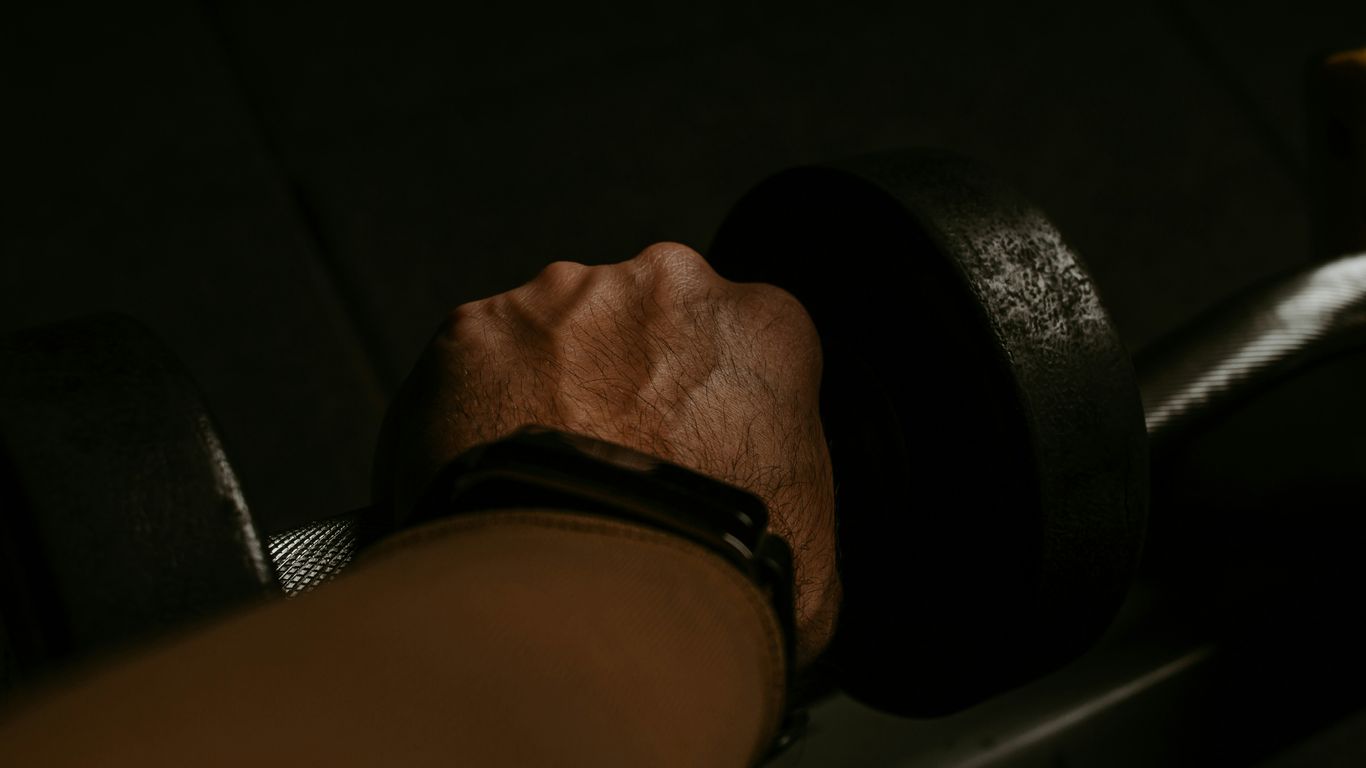 a person's hand holding a barbell in the dark