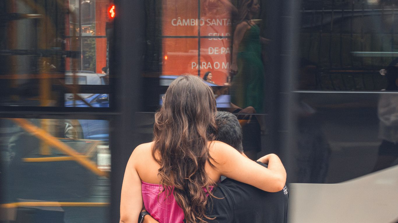 A couple hugs each other while waiting outside.