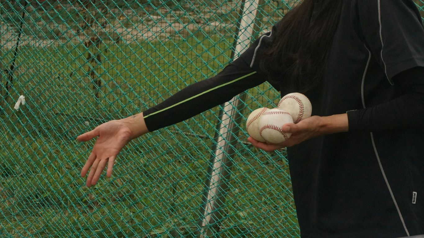 woman in black long sleeve shirt holding white baseball ball