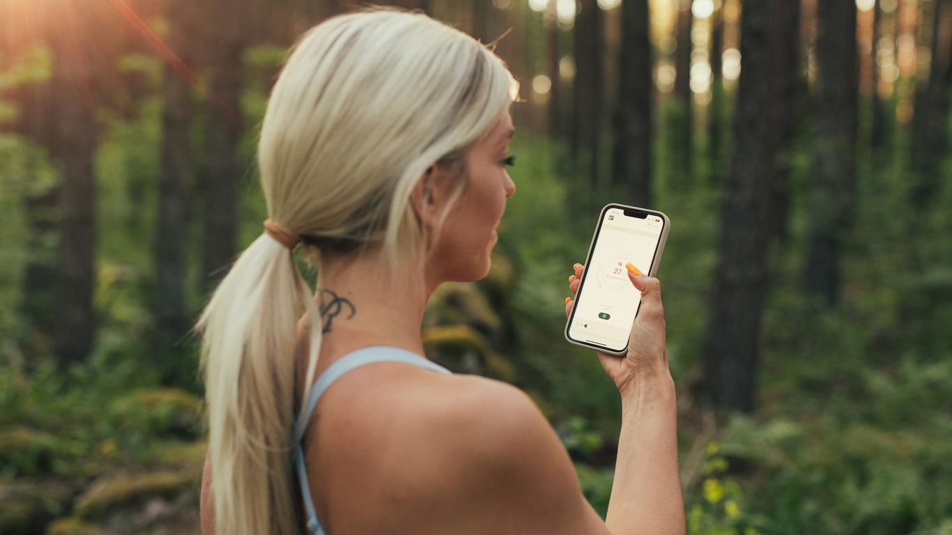 a woman holding a cell phone in a forest