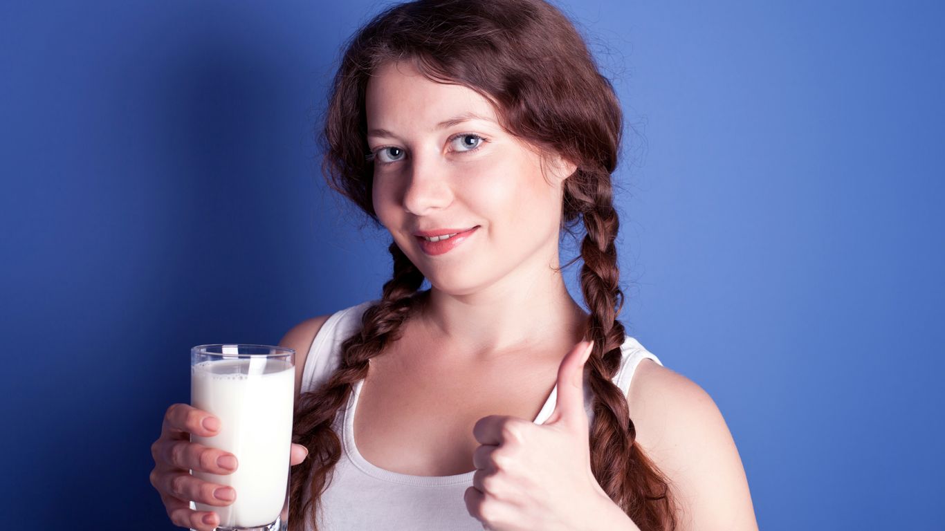 A woman is holding a glass of milk