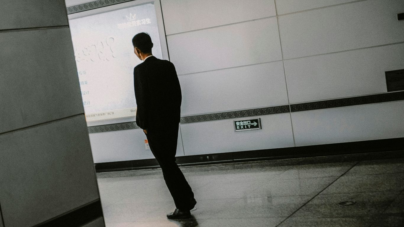 a man in a suit standing in front of a wall