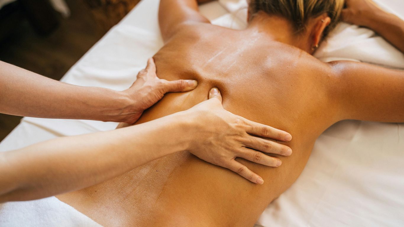 Person receiving a relaxing back massage on a white table.