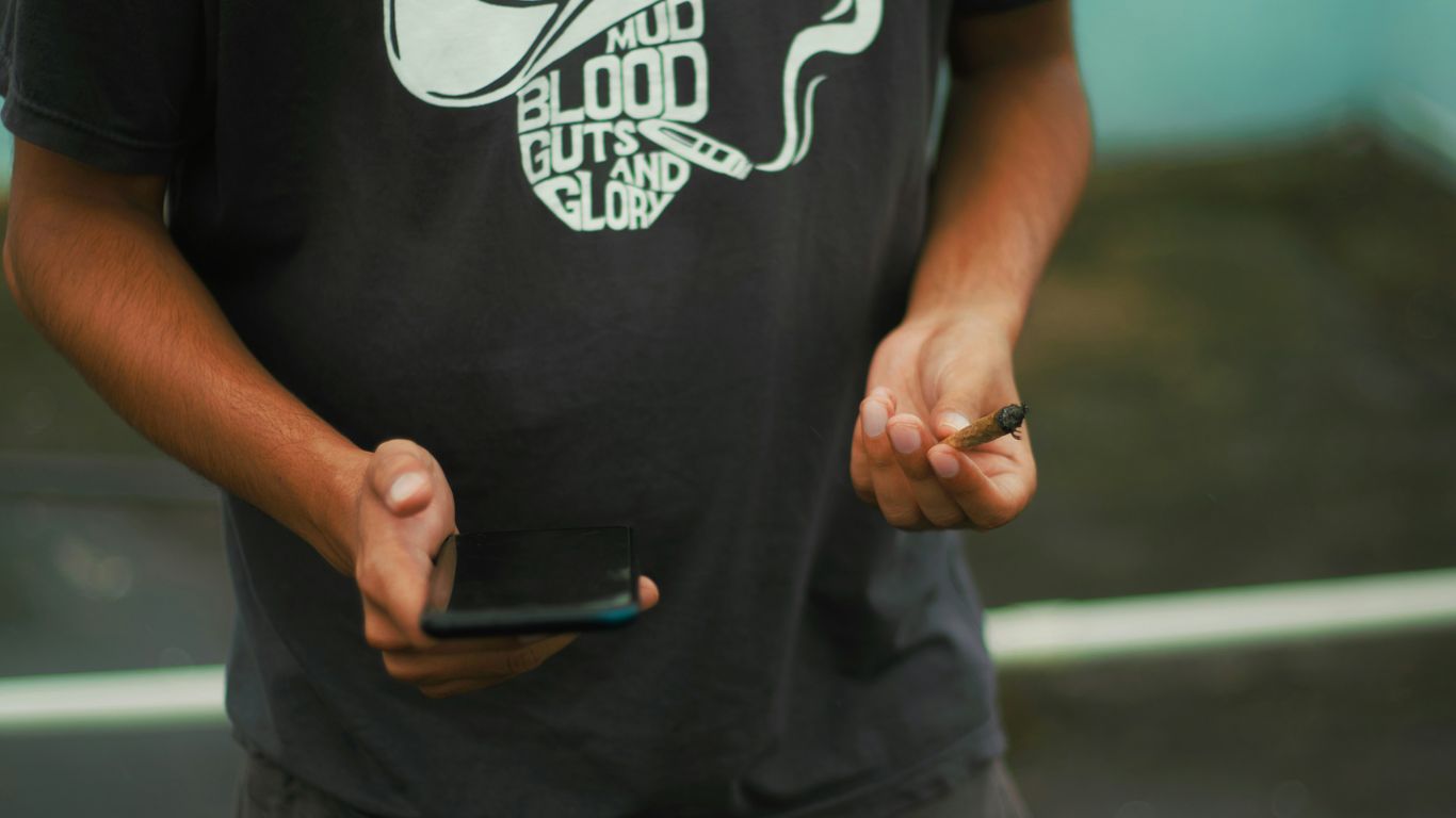 man in black and white crew neck t-shirt holding black smartphone