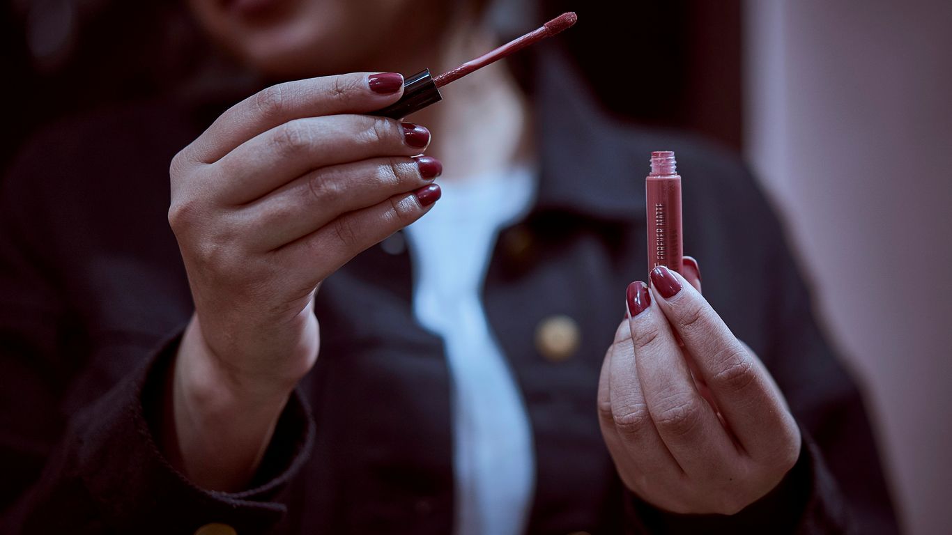 person holding red pen and writing on paper