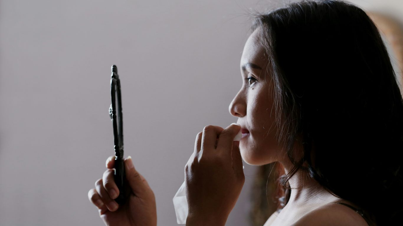 woman looking to mirror and wiping her lips