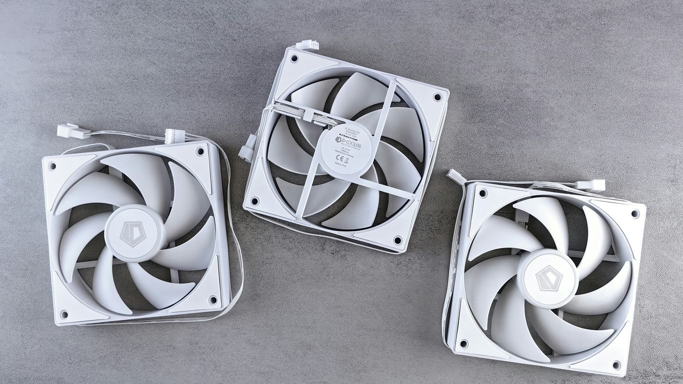 three white fans sitting on top of a cement floor