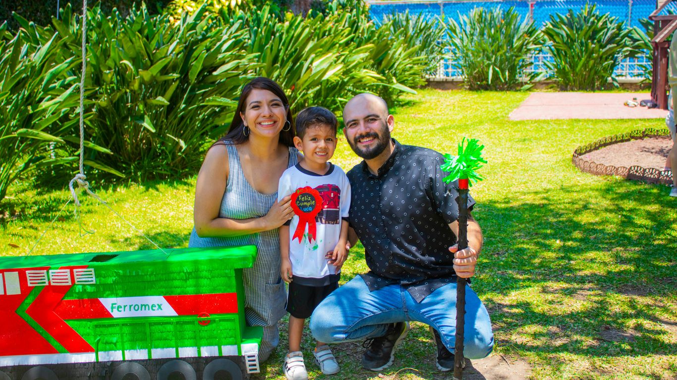 a man and a woman pose with a child in front of a train