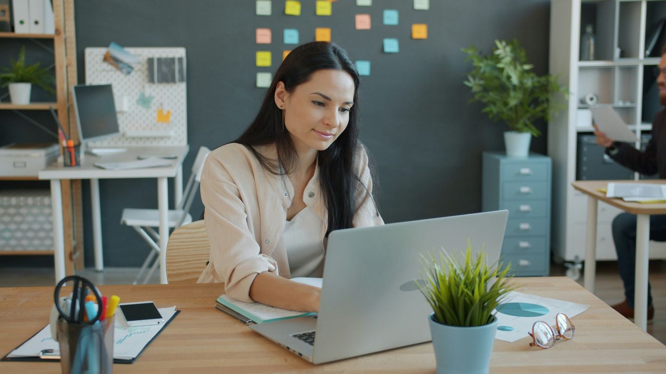 Woman working on a laptop at an office desk.