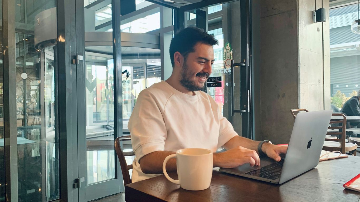 Man smiling while working on laptop in cafe.