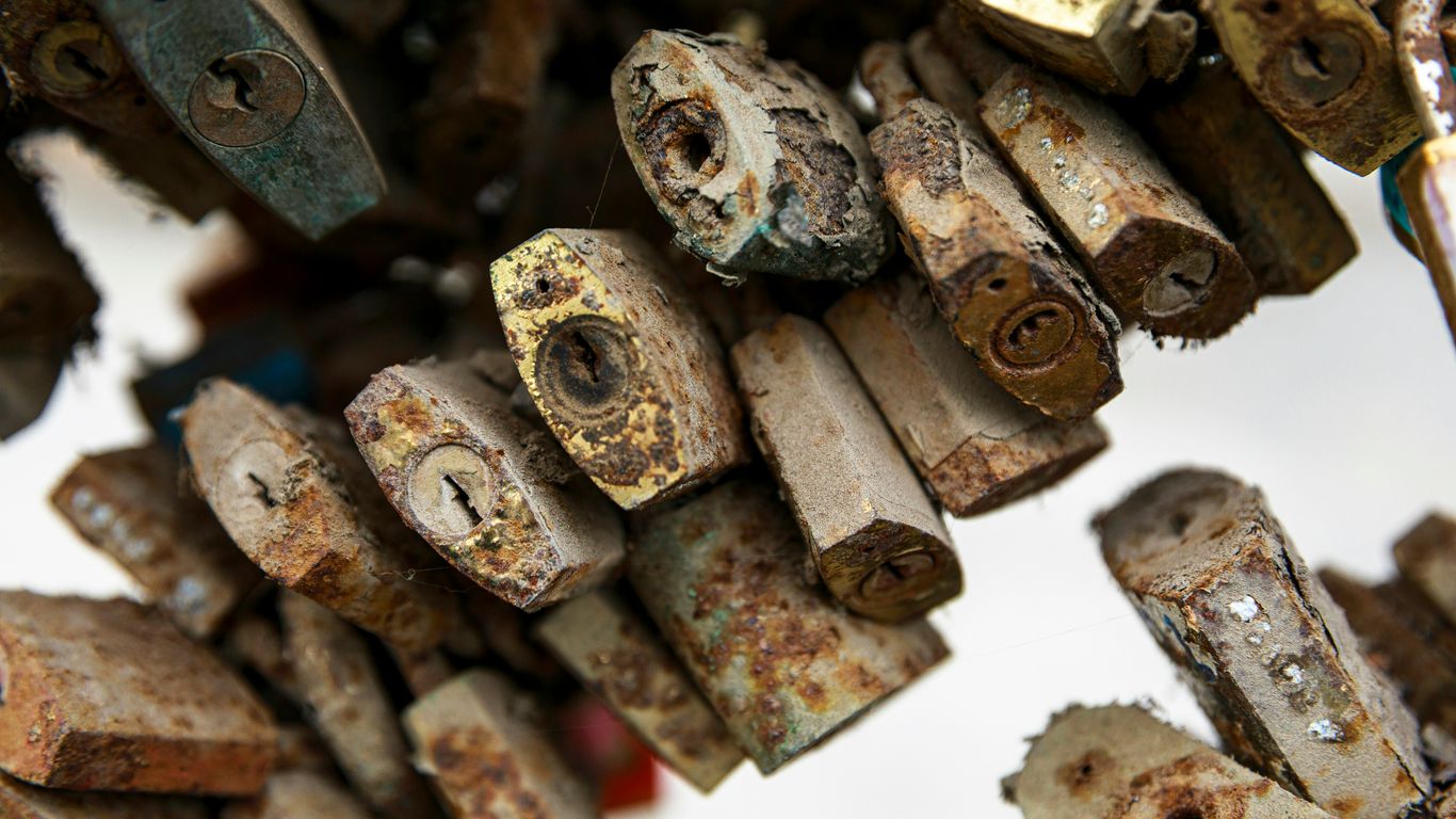 A collection of old, rusty padlocks hanging together.