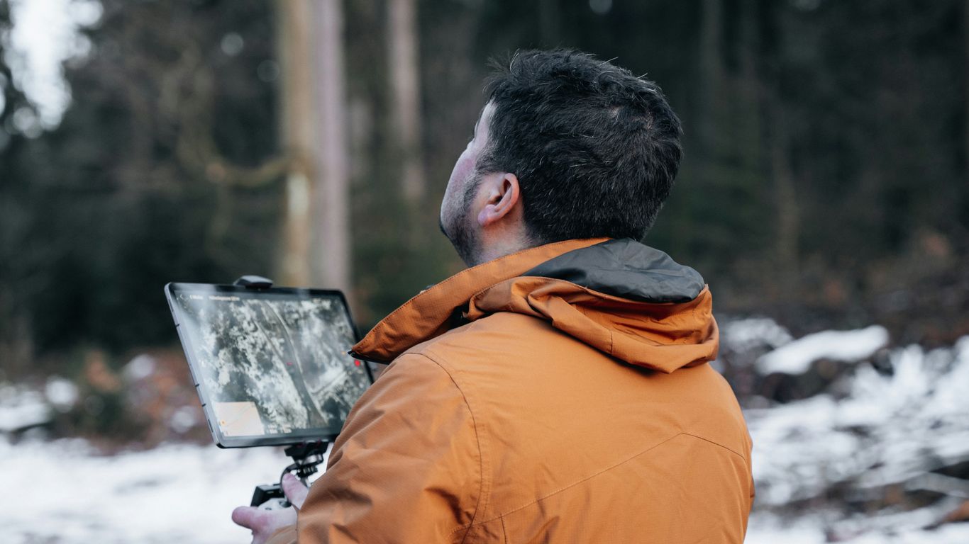 a man in an orange jacket holding a camera