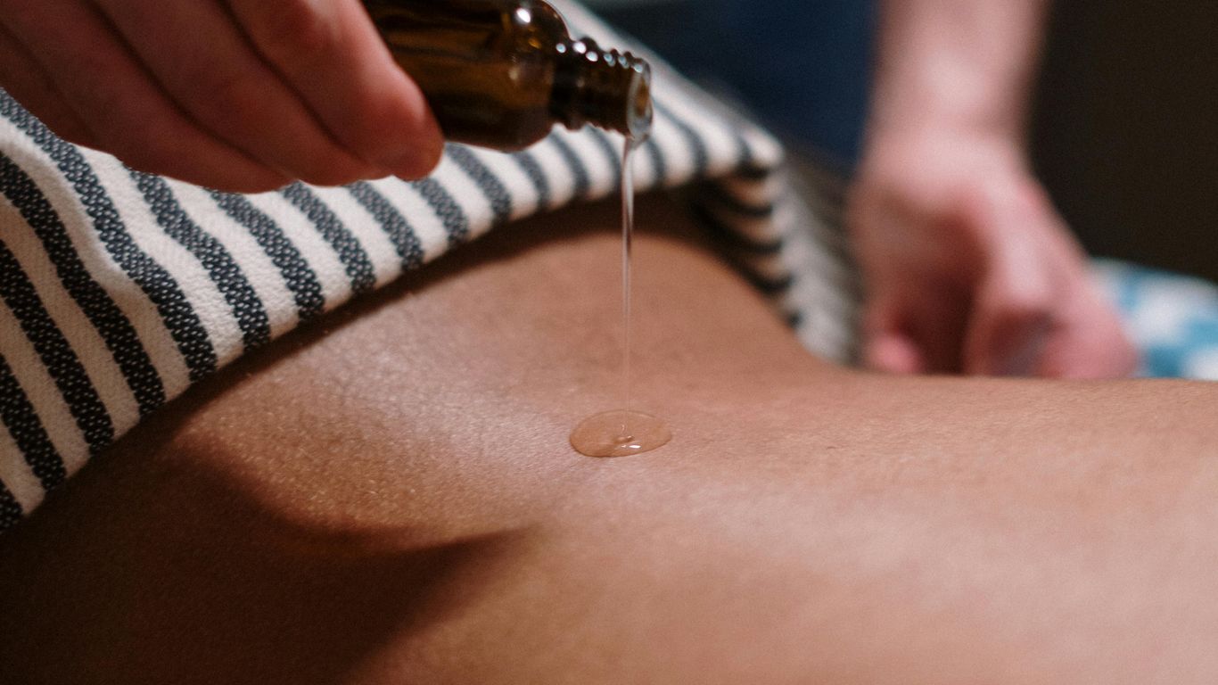 Massage oil being poured onto someone's back during a massage.
