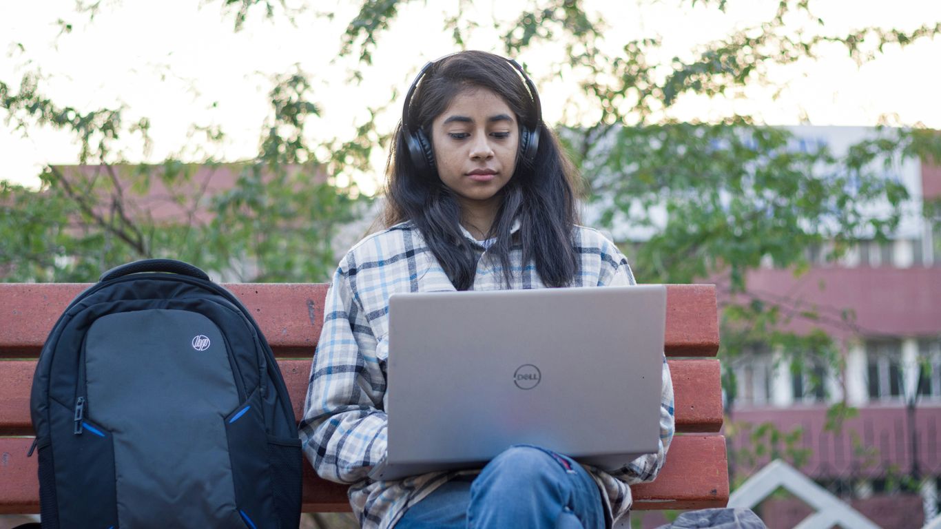 a woman sitting on a bench using a laptop computer