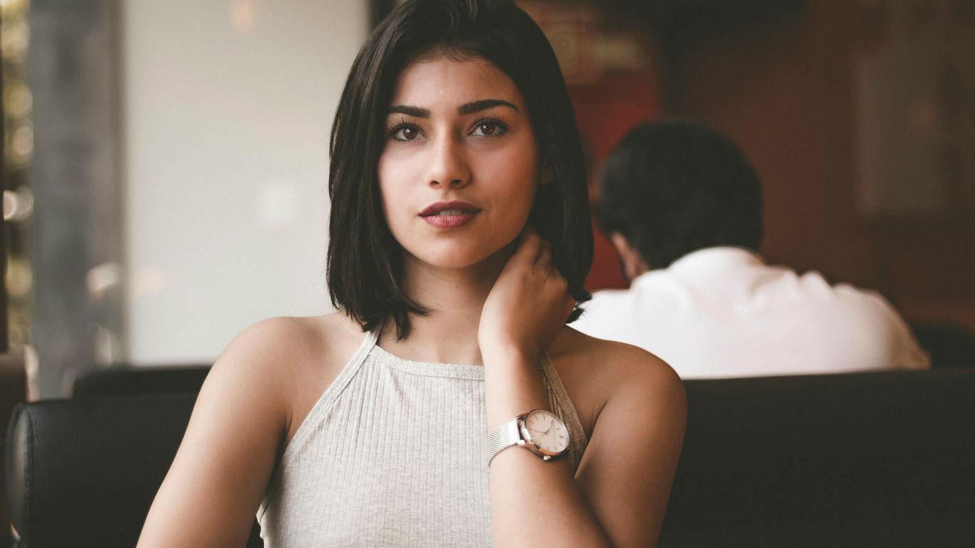 woman wearing gray spaghetti strap shirt sitting on black leather sofa close-up photo