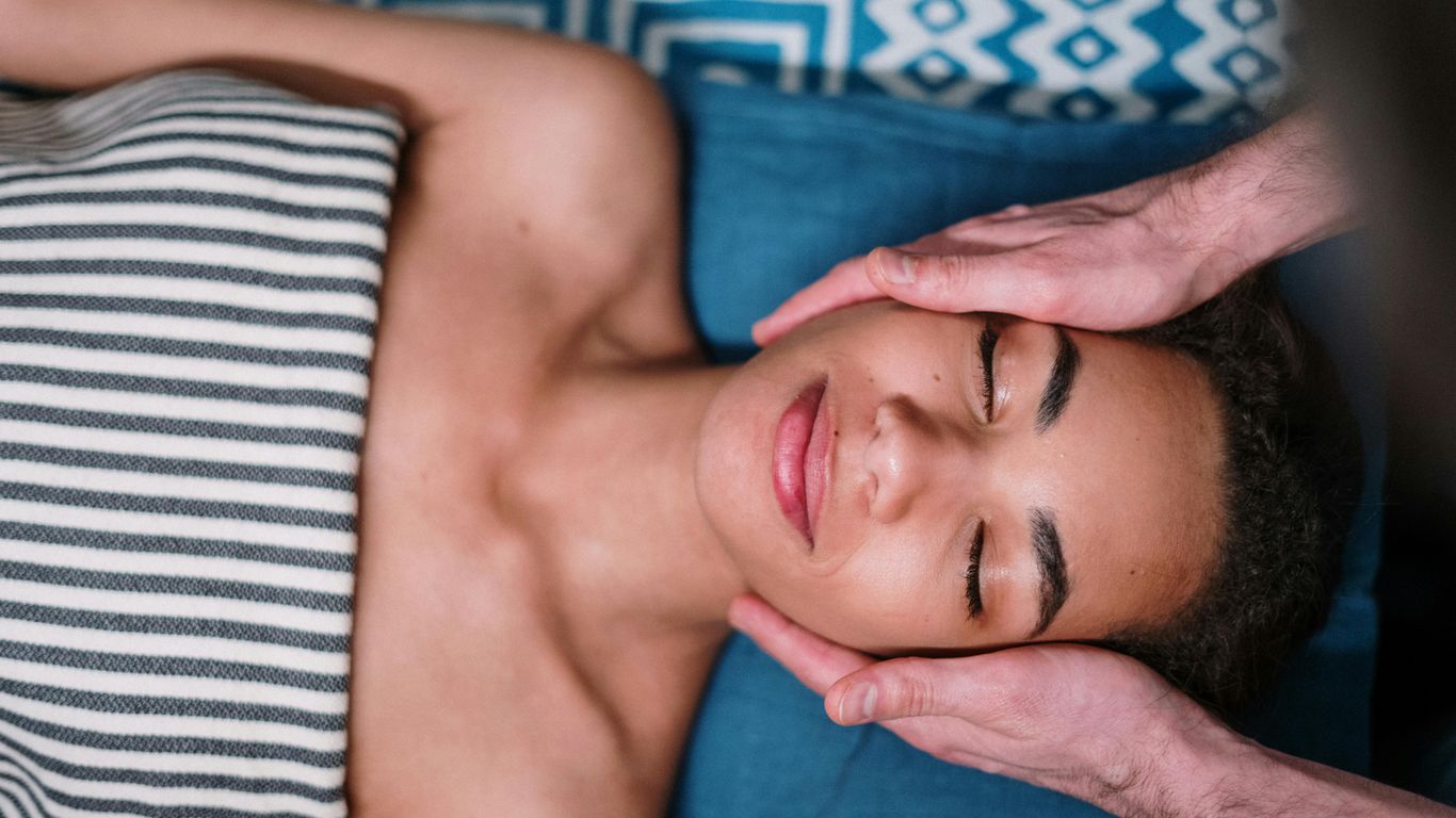 Person receiving a relaxing facial massage, eyes closed, peaceful atmosphere.