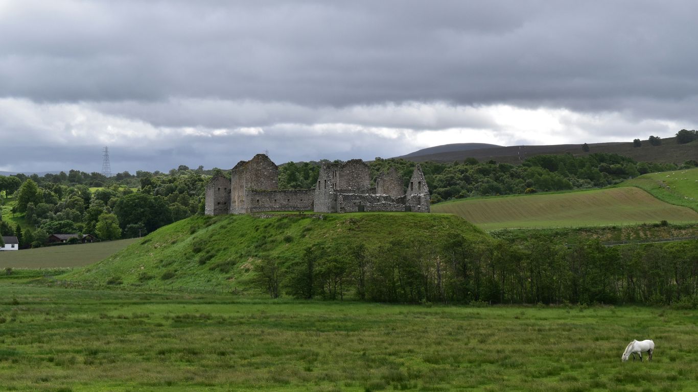 gray concrete building on green grass field under cloudy sky during daytime