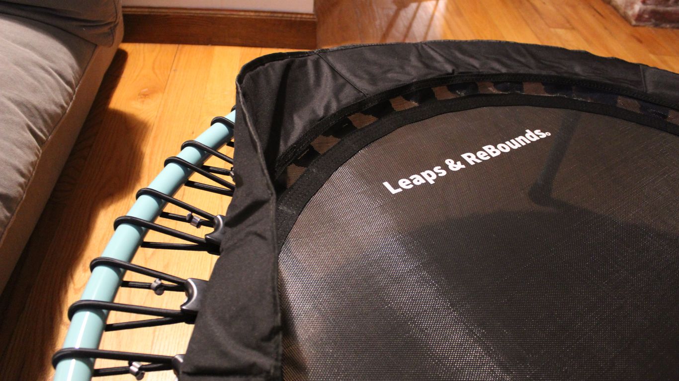 Small indoor trampoline with 'Leaps & ReBounds' logo, wooden floor.